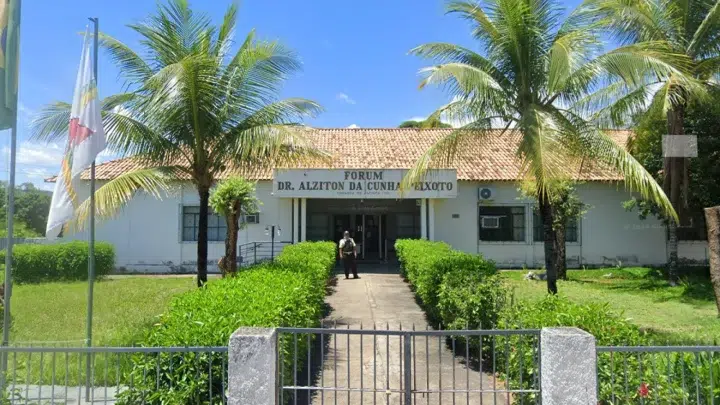 Fachada de um fórum de justiça ao ar livre, com placa “FORUM DR. ALZITON DA CUNHA MARINHO” e palmeiras ao redor